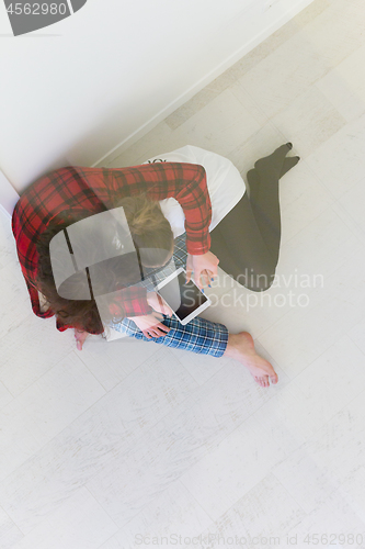 Image of Young Couple using digital tablet on the floor