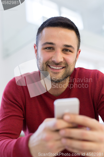 Image of young man using a mobile phone  at home