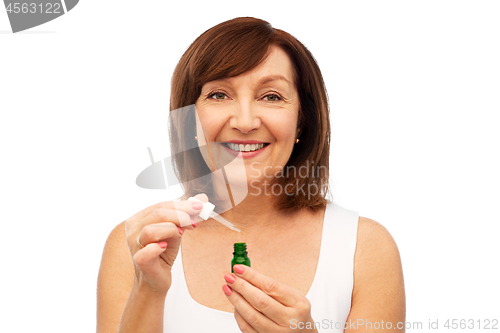 Image of smiling senior woman with bottle of serum