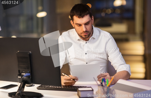 Image of businessman with papers working at night office