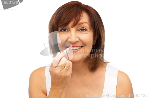 Image of smiling senior woman applying lipstick to her lips