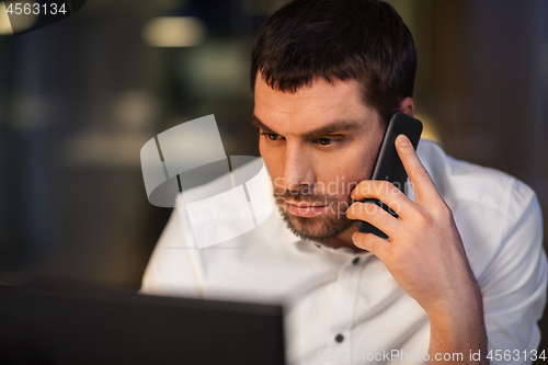 Image of businessman calling on smartphone at night office