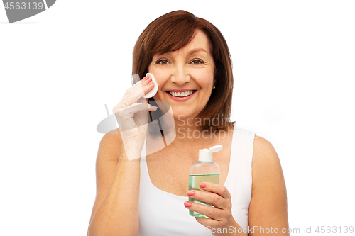 Image of senior woman cleaning face by lotion on cotton pad