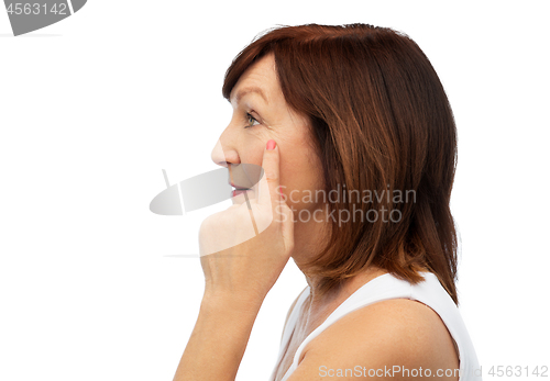 Image of profile of senior woman pointing to eye wrinkles