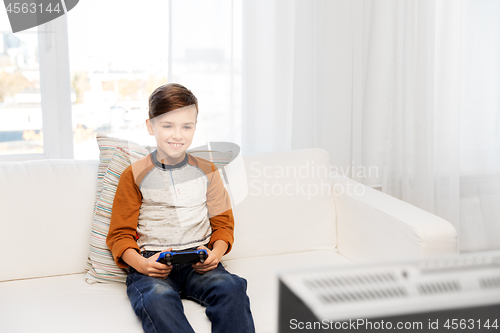 Image of happy boy with gamepad playing video game at home