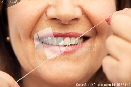Image of senior woman cleaning her teeth by dental floss