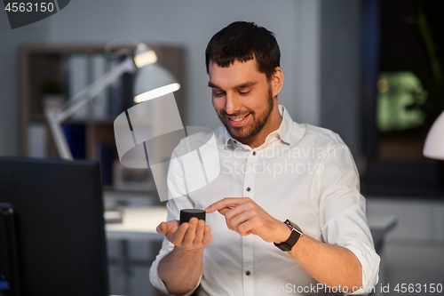 Image of businessman using smart speaker at night office