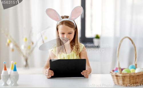 Image of happy girl with tablet pc and easter eggs at home