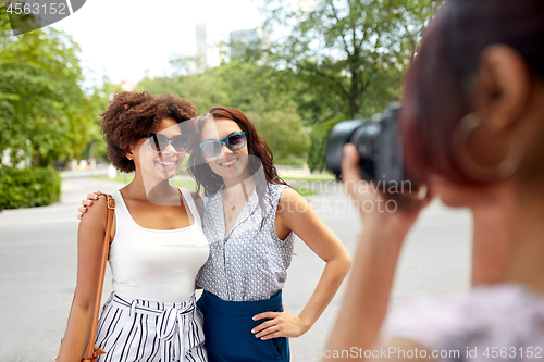 Image of woman photographing her friends in summer park