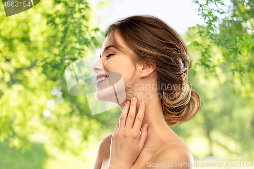 Image of smiling young woman touching her neck