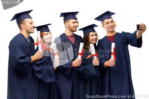 Image of graduates with diplomas taking selfie by cellphone