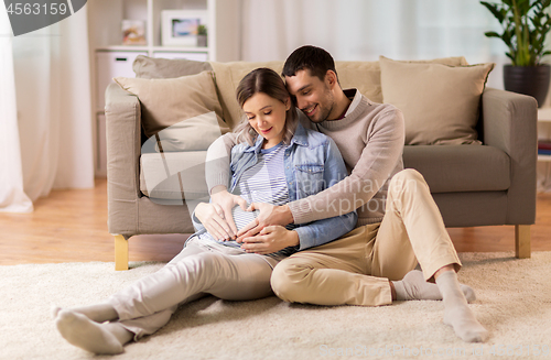 Image of man with pregnant woman making hand heart at home