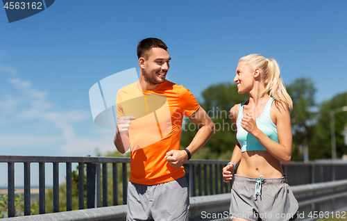 Image of couple with fitness trackers running along bridge