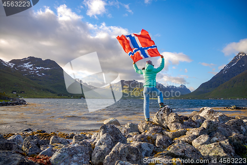 Image of Woman with a waving flag of Norway on the background of nature