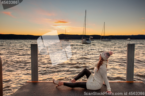 Image of Woman watching a cool winter sunset from the jetty