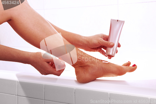 Image of woman applying cream on foot