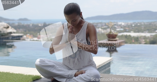 Image of Relaxed barefooted lady sitting in lotus position near swimming pool