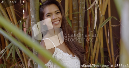 Image of Pretty smiling woman leaning on bamboo tree