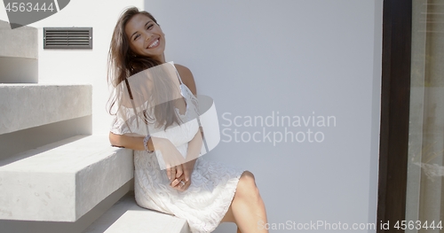 Image of Cheerful young woman sitting on stairs