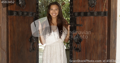 Image of Cheerful woman opening old wooden doors