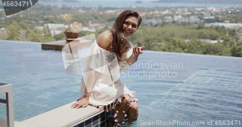 Image of Attractive woman having fun while resting beside swimming pool in hotel