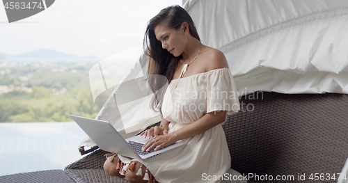 Image of Relaxed woman using laptop on terrace against beautiful landscape