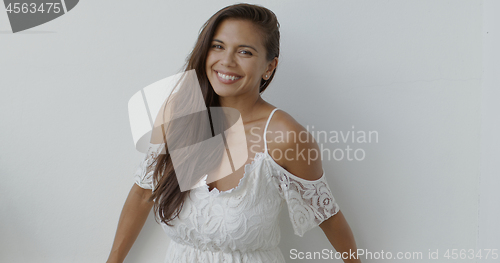 Image of Happy young woman in white dress looking at camera