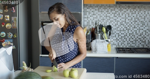 Image of Woman cutting apples on board in kitchen