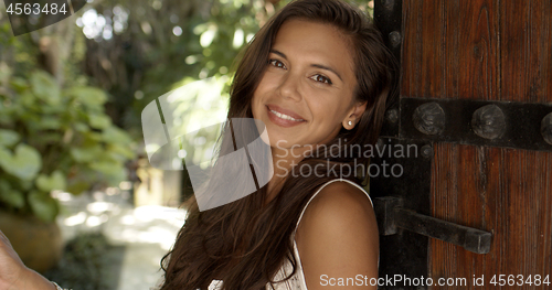 Image of Pretty woman standing in doorway and enjoying sunny day