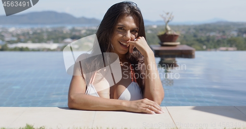 Image of Happy young brunette in pool looking at camera