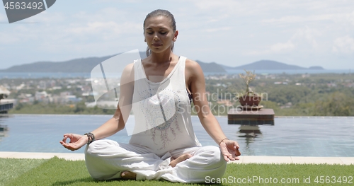 Image of Lady practicing yoga in lotus pose against ocean coast