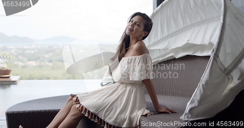 Image of Serene pleased woman contemplating while resting on terrace at resort