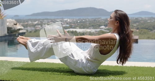 Image of Calm tourist practicing yoga in balancing asana poolside against town on coast