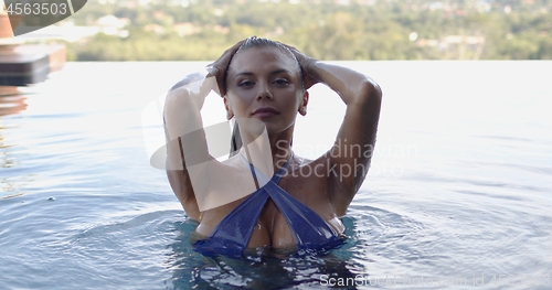 Image of Serene contented slim adult lady resting in swimming pool against landscape in sunny day