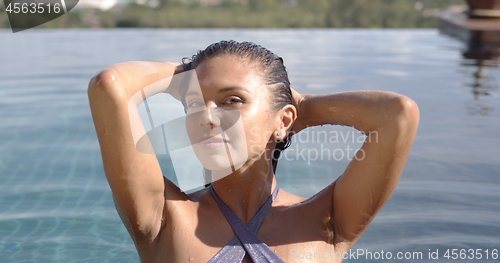 Image of Gorgeous woman in swimming pool at resort in sunlight