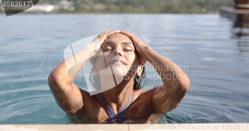 Image of Pleased adult woman resting in swimming pool in sunny day