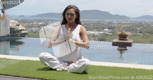 Image of Calm lady sitting in lotus position at resort