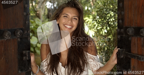 Image of Joyful young woman standing in doorway