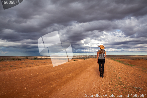 Image of Farm girl watching storm over the arid desert