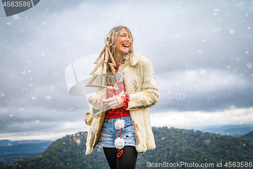 Image of Woman holding Christmas items in snowy mountain scene