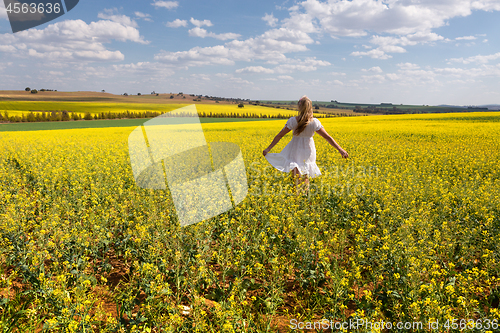 Image of Country girl frollicking in fields of golden canola