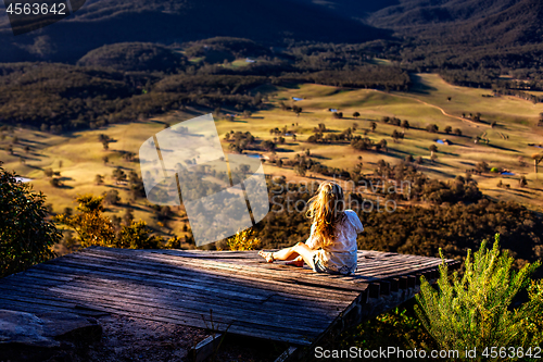 Image of Female sitting on timber ramp taking in mountain valley veiws in