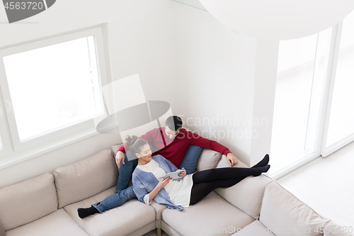 Image of couple relaxing at  home with tablet computers