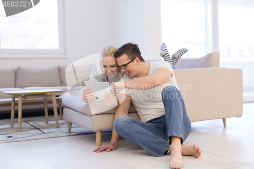 Image of couple relaxing at  home with tablet computers