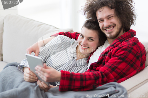 Image of couple relaxing at  home with tablet computers