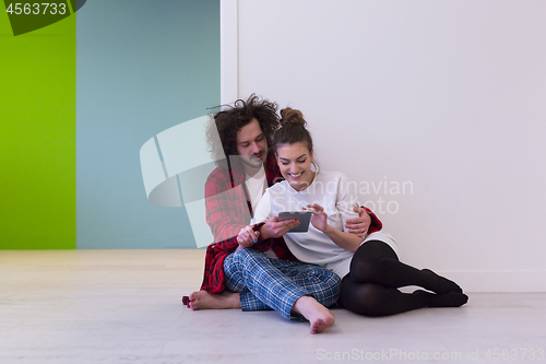 Image of Young Couple using digital tablet on the floor