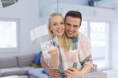 Image of couple showing small red house in hands