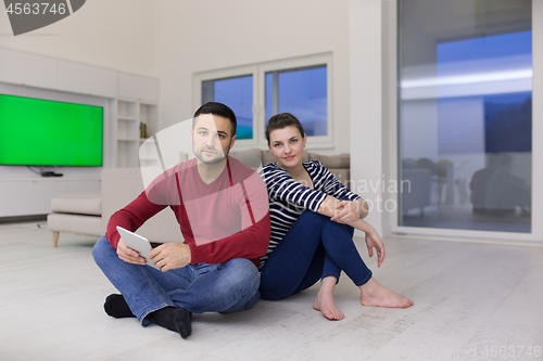 Image of Young Couple using digital tablet on the floor