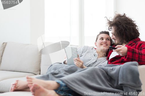 Image of couple relaxing at  home with tablet computers