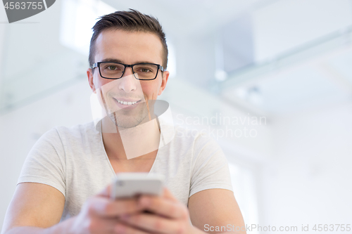 Image of young man using a mobile phone  at home